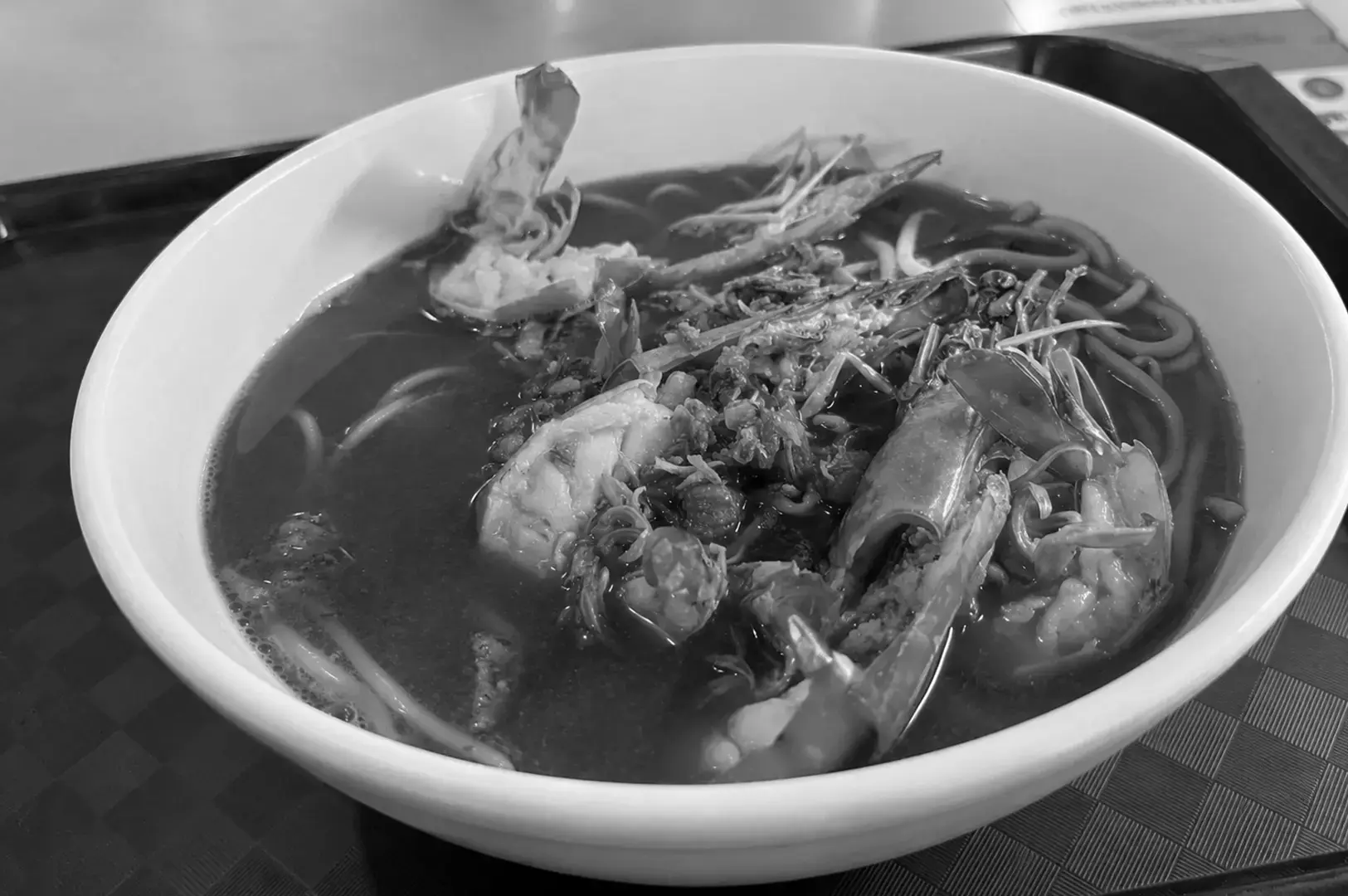 Close-up of a hearty bowl of prawn noodle soup with fresh prawns.