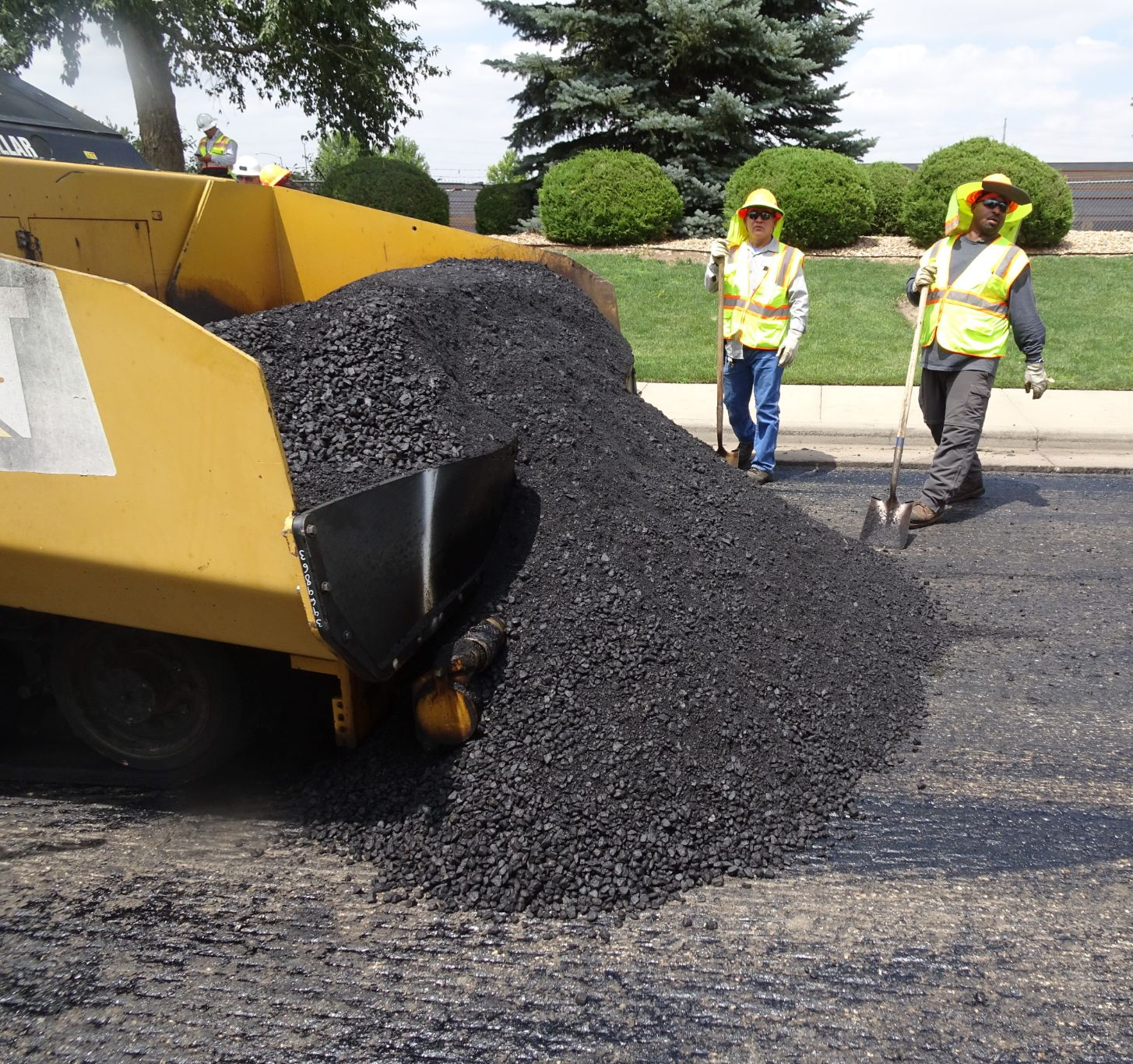 A photo of a dump truck unloading asphalt material for a paving project
