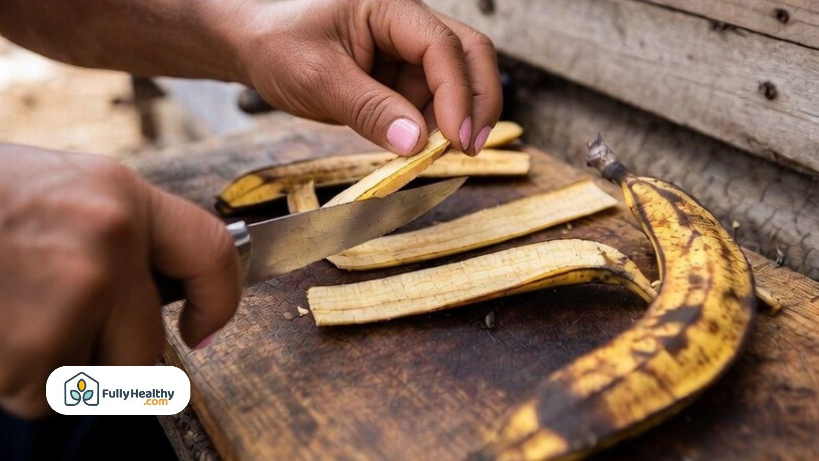Hands slicing banana peels into thin strips on a wooden cutting board for chicken feed preparation.