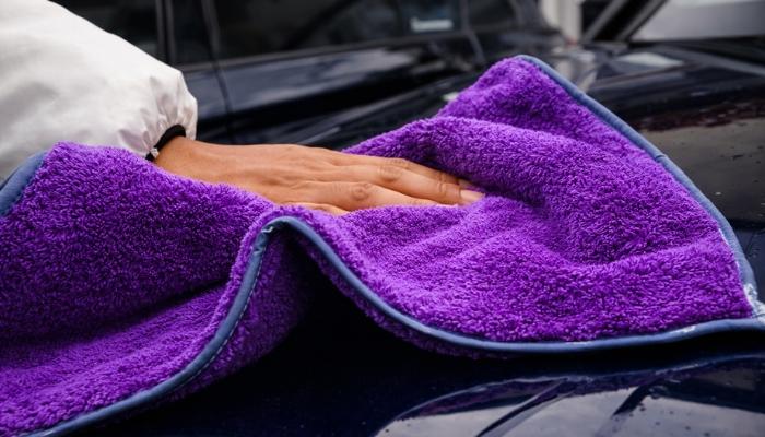 A microfiber towel is being used to clean the car's surface