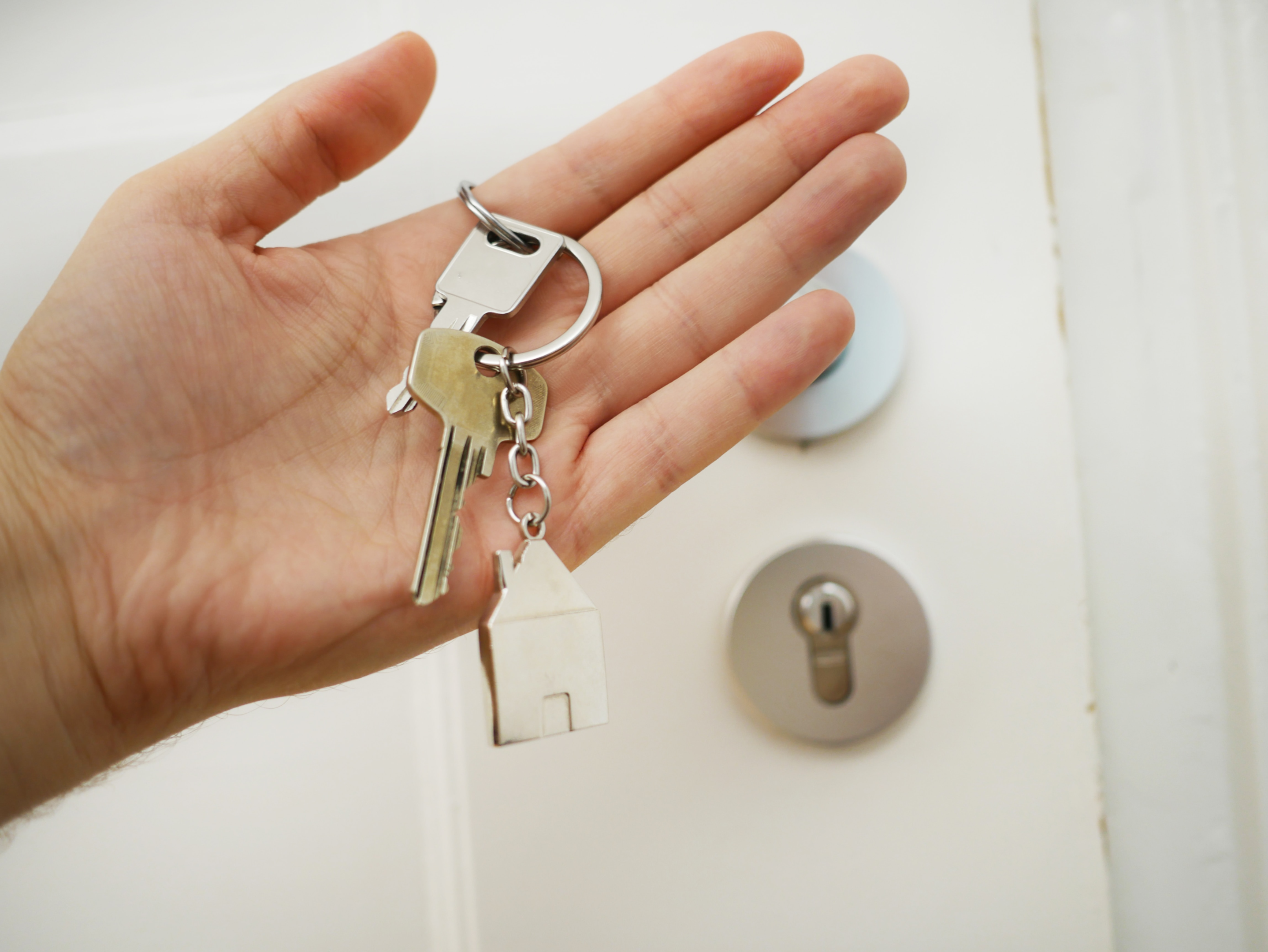 Access keys in a person's hand with the door lock in the background