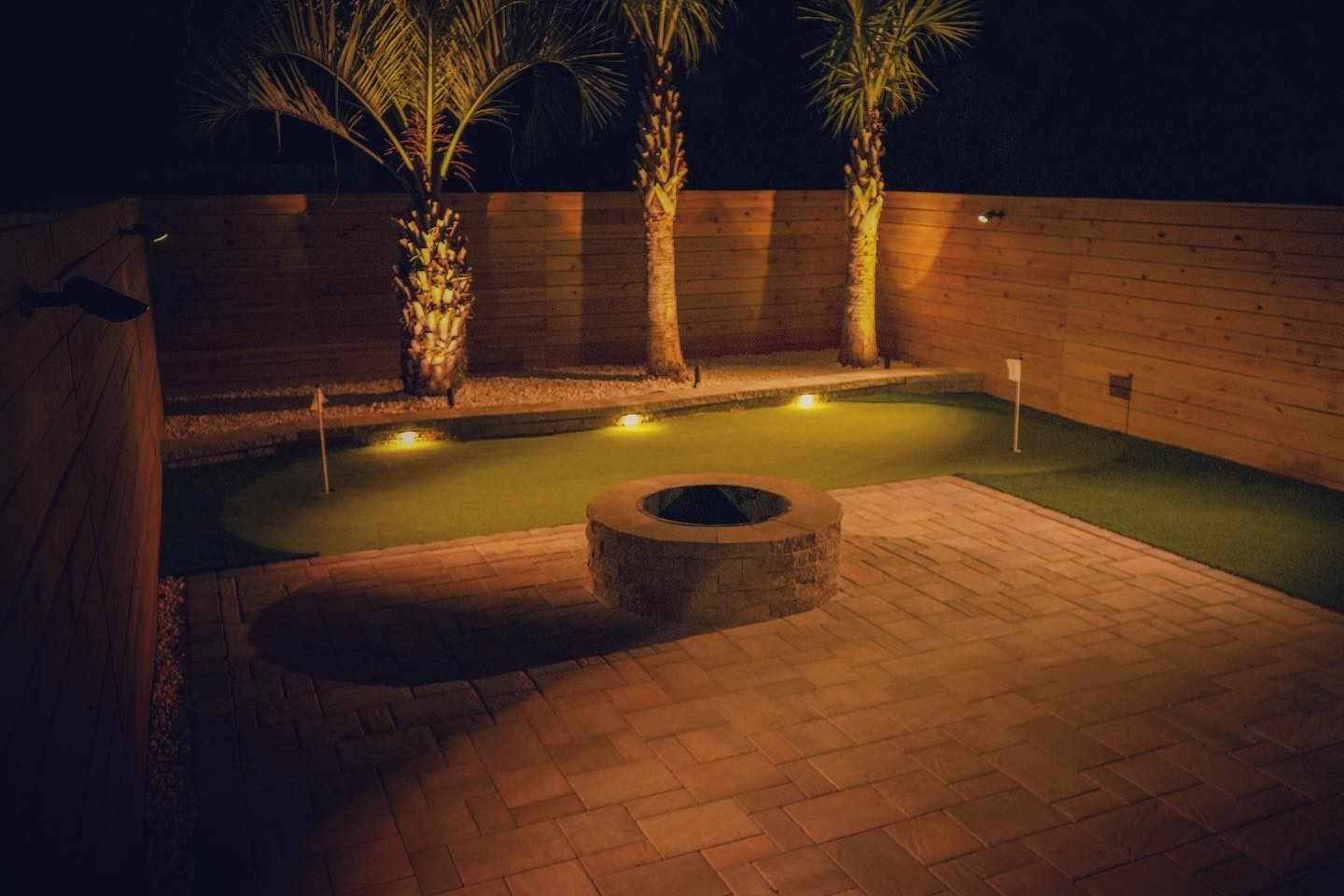 Outdoor lighting project in a beautiful back yard in Greensboro, NC includes palm trees and a artifical turf putting green.