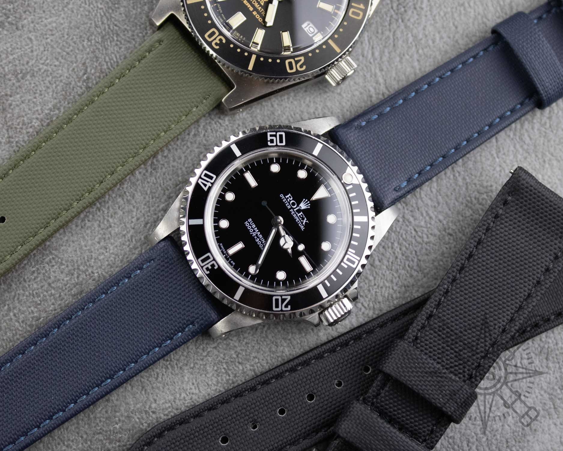 A close-up view of a navy blue sailcloth watch strap on a wrist.