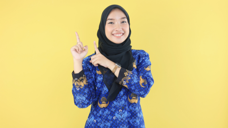 Portrait of a woman wearing a batik uniform on a yellow background.