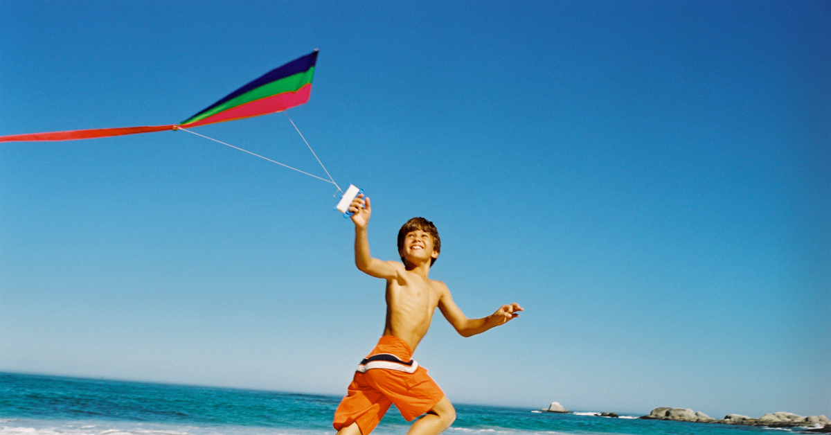 Child flying a colorful kite on the beach during a sunny Jersey Shore day in Lavallette NJ