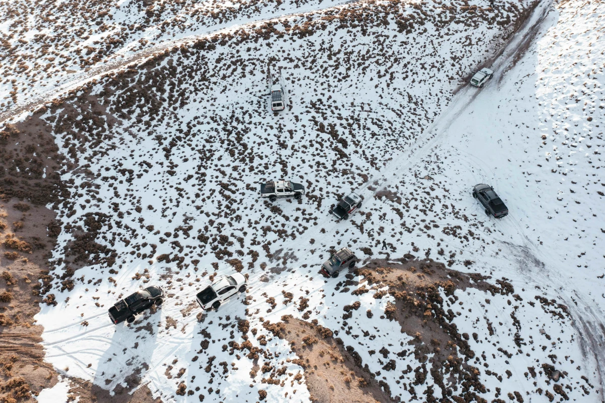 Aerial view of seven off-road vehicles on a snowy ridge