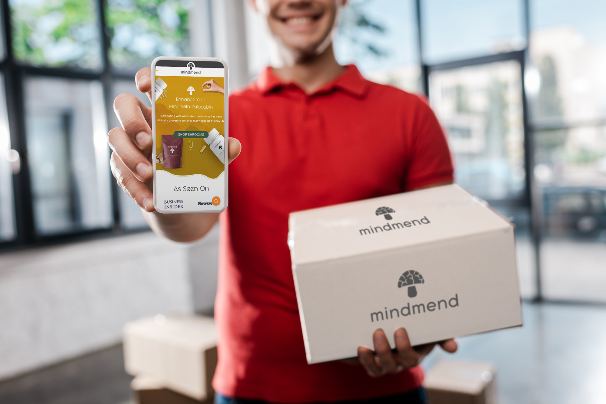 man smiling holding a phone and a box