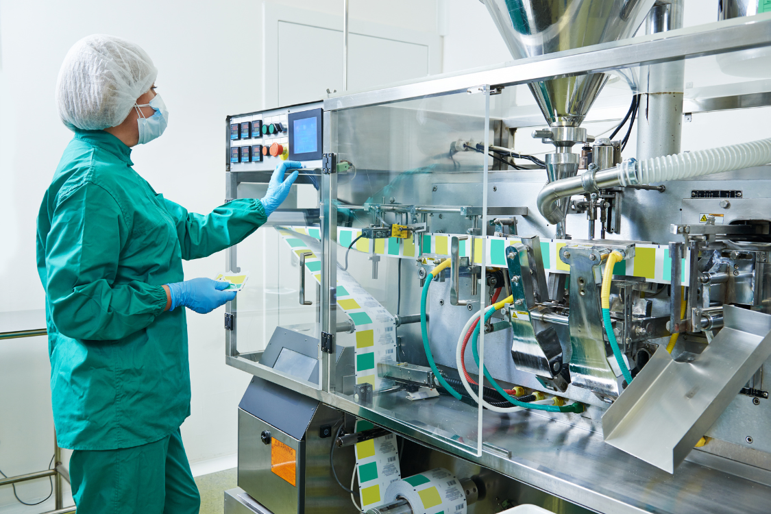 Worker operating supplement packaging machine in GMP-certified facility