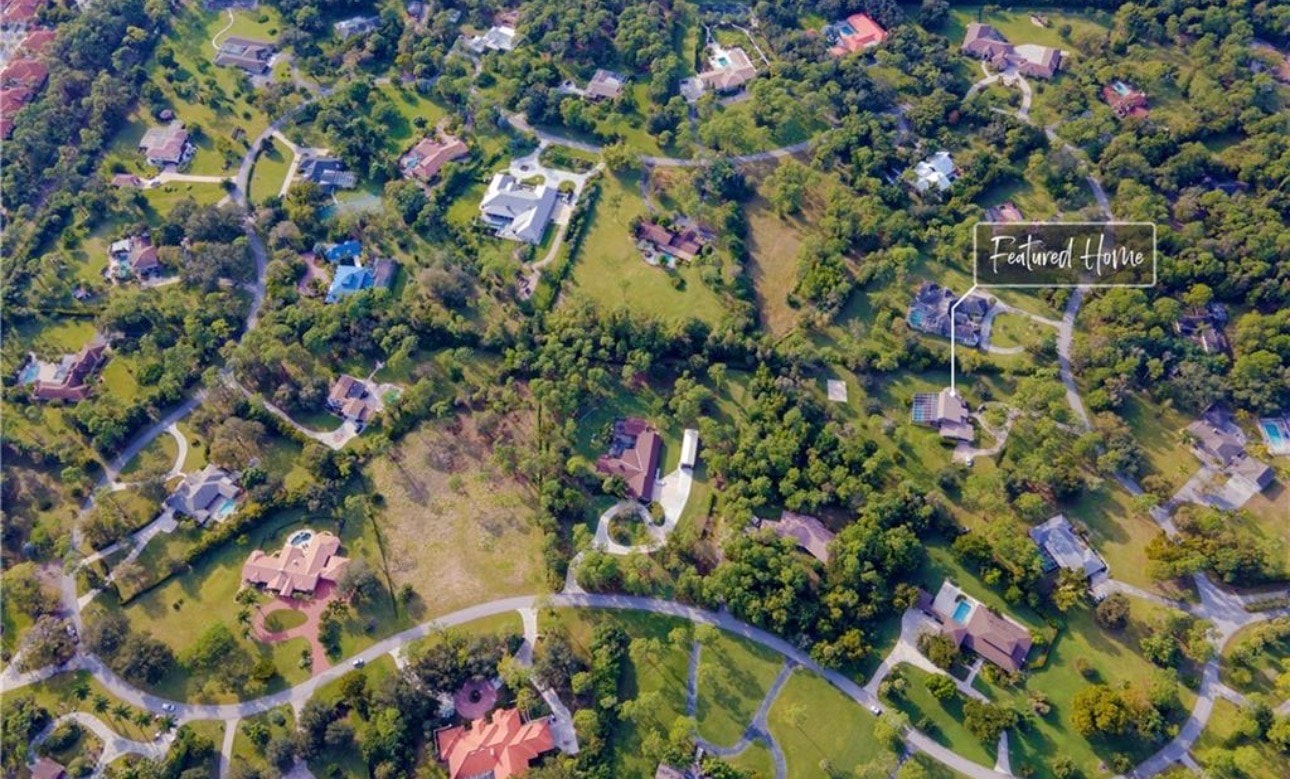 The image showcases an elegant swimming pool and spa area, surrounded by mature palm trees and lush landscaping, creating a serene oasis in the Brynwood neighborhood of Fort Myers. The setting emphasizes maximum privacy and relaxation, perfect for residents seeking a tranquil escape.
