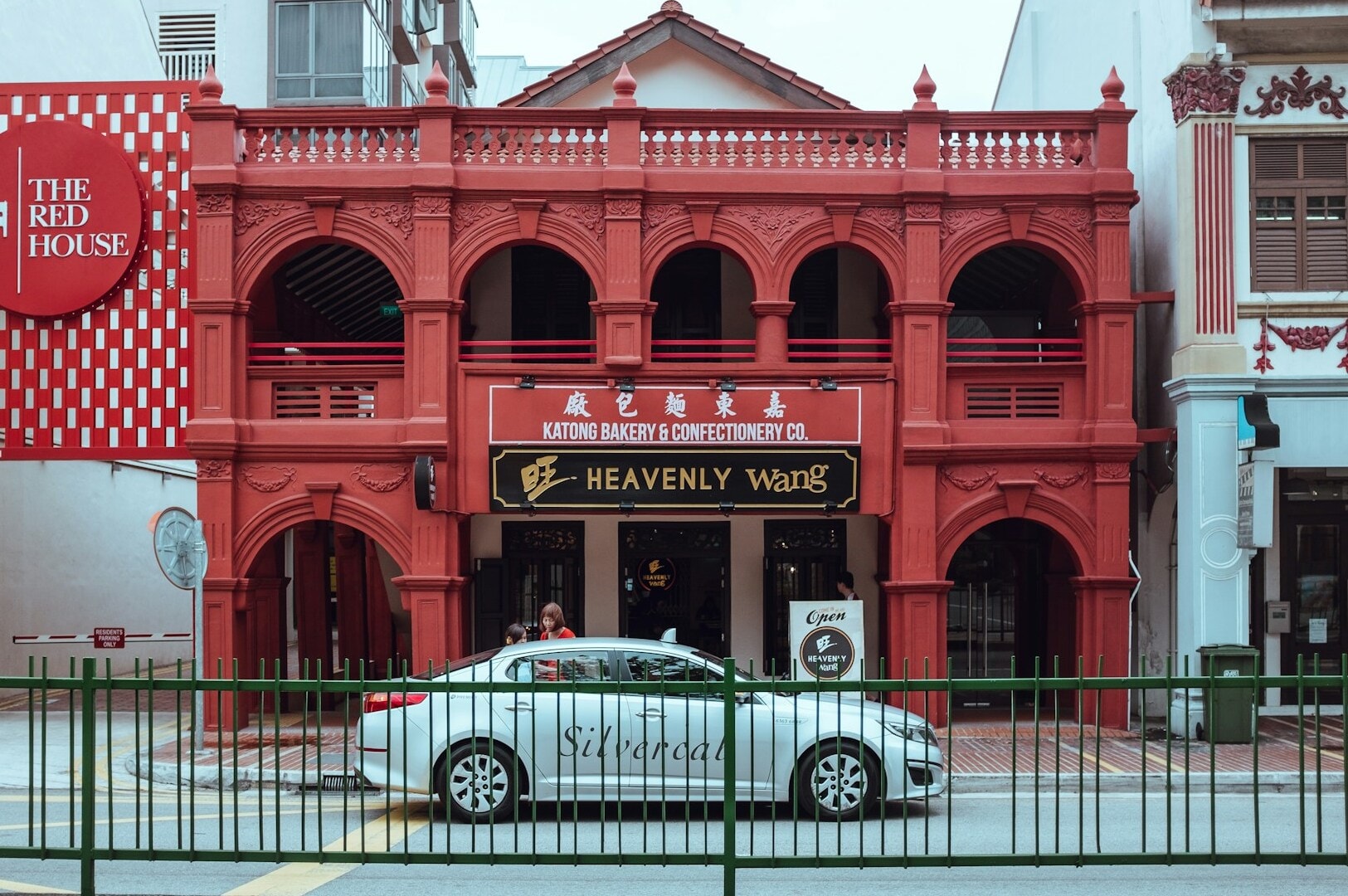 A parked car in front of a vibrant red building, showcasing a restaurant in Singapore.