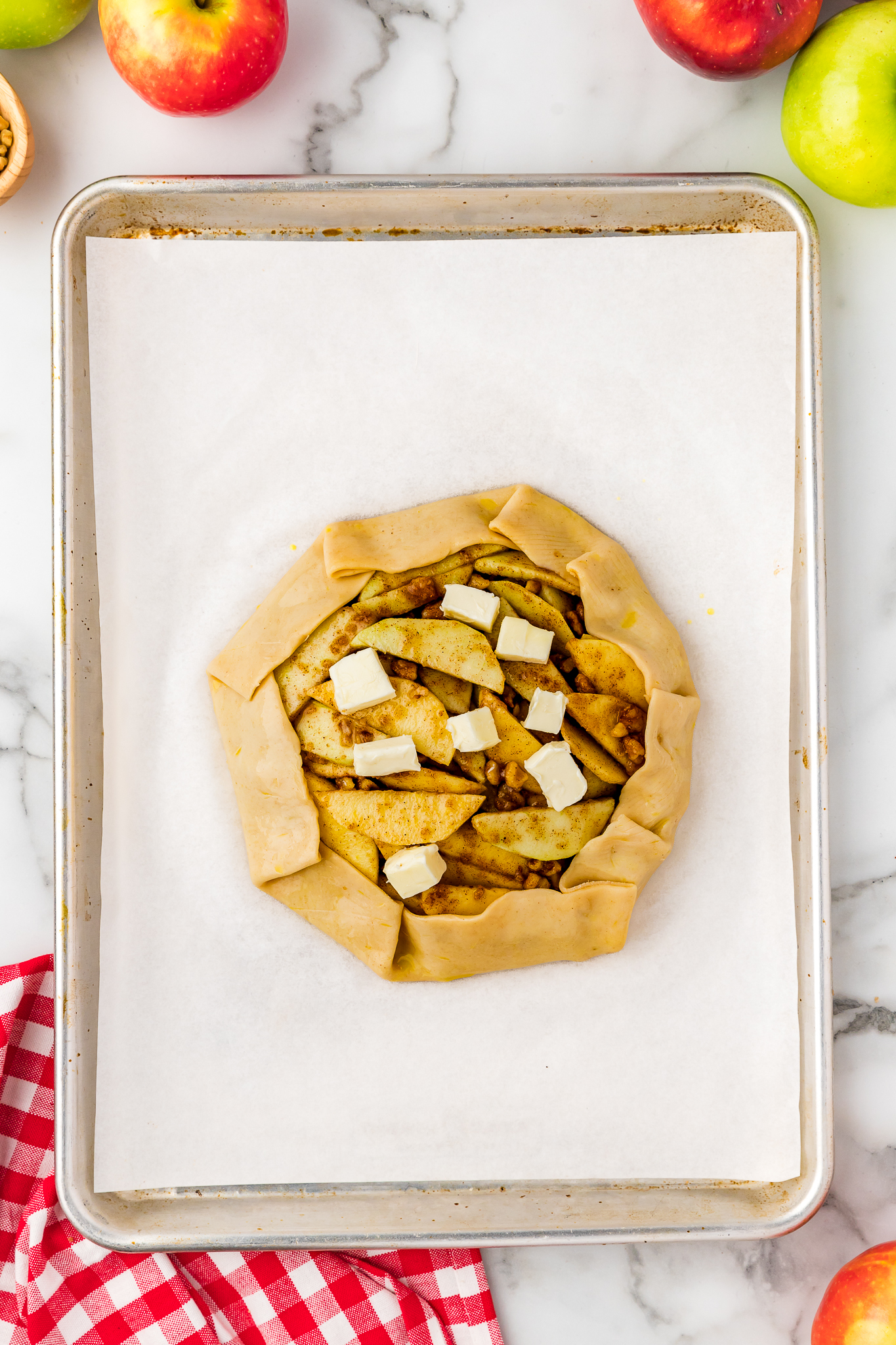 unbaked apple crostata on baking sheet topped with butter