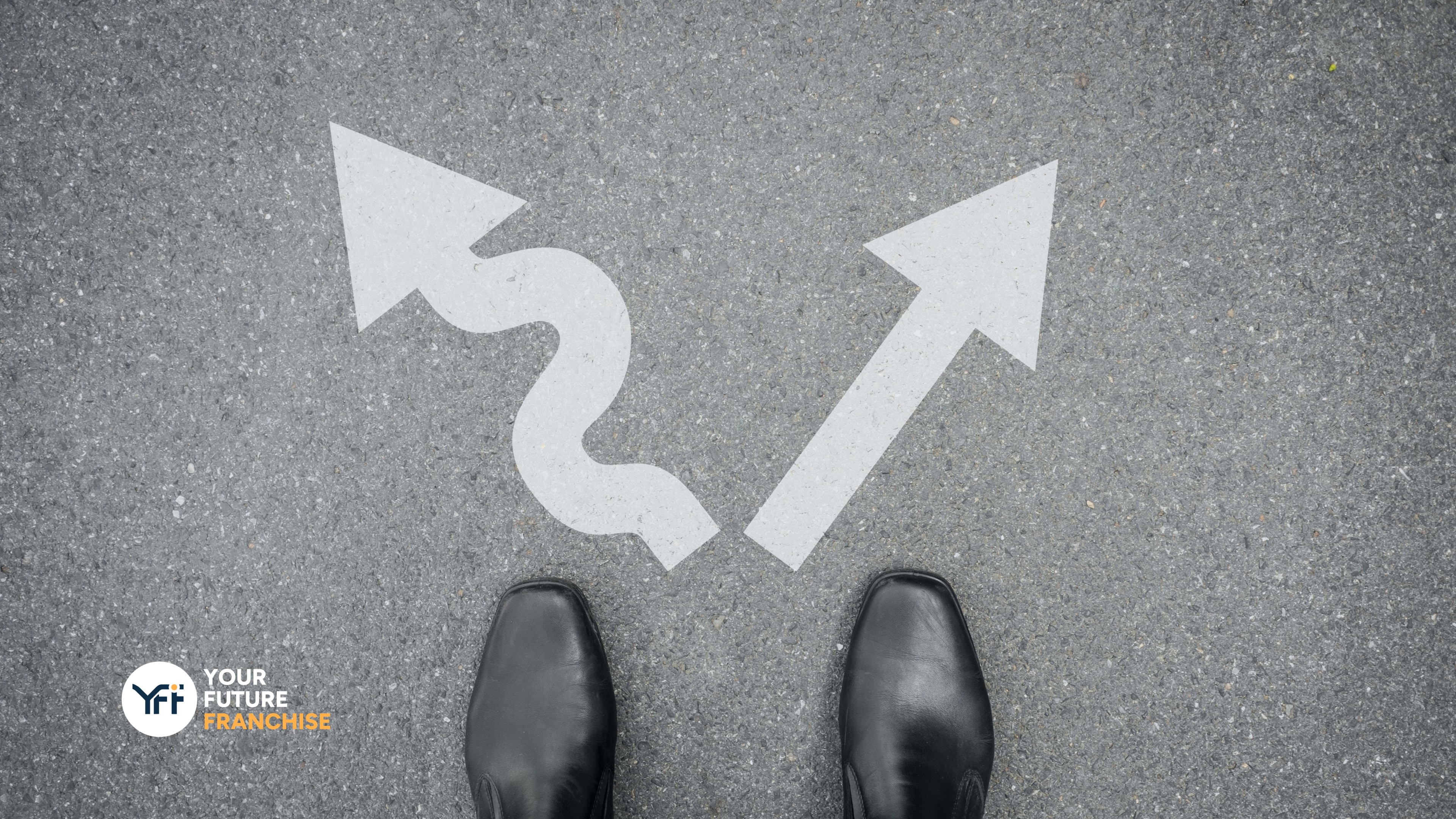 At a cross roads in decision making. Two arrow pointing in different directions by a business mans feet.