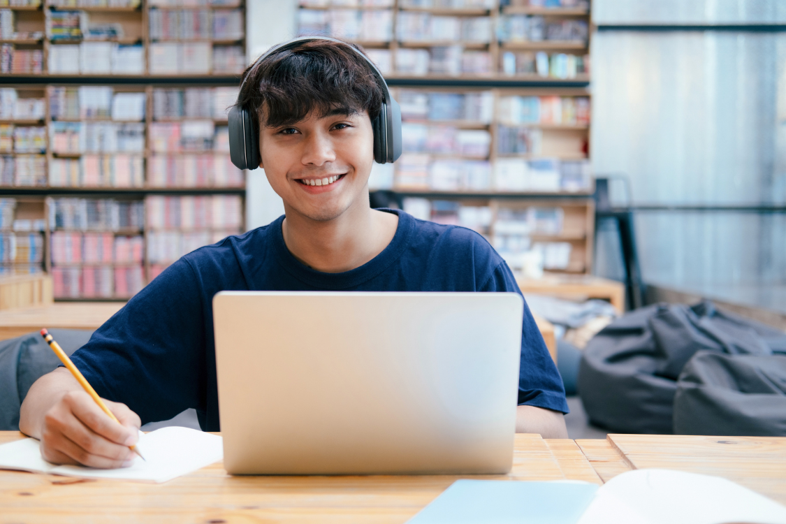 A Filipino student wearing headphones while studying remotely, ideal for virtual internships and online hiring.