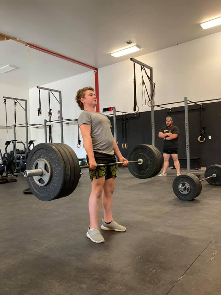 Group of people of different ages and skill levels doing CrossFit exercises in a gym