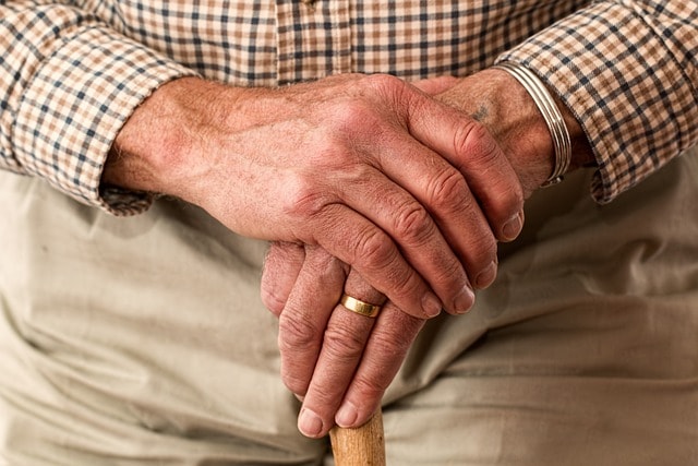 Close-up of older hands on a cane