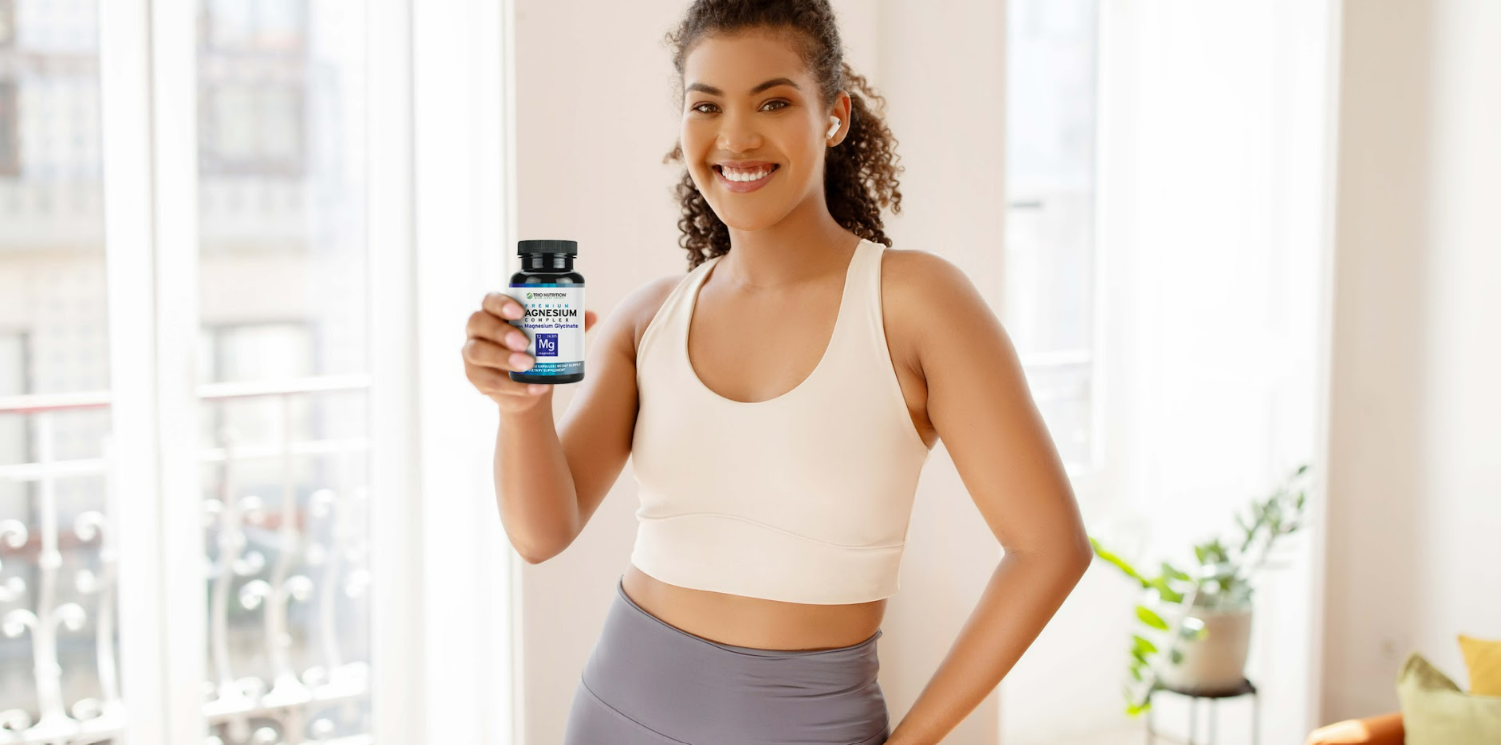 woman standing and holding Trio Nutrition’s Magnesium Complex