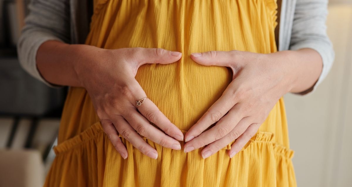 Surrogate holding her hands over her pregnant belly knowing that her health and safety is vital 