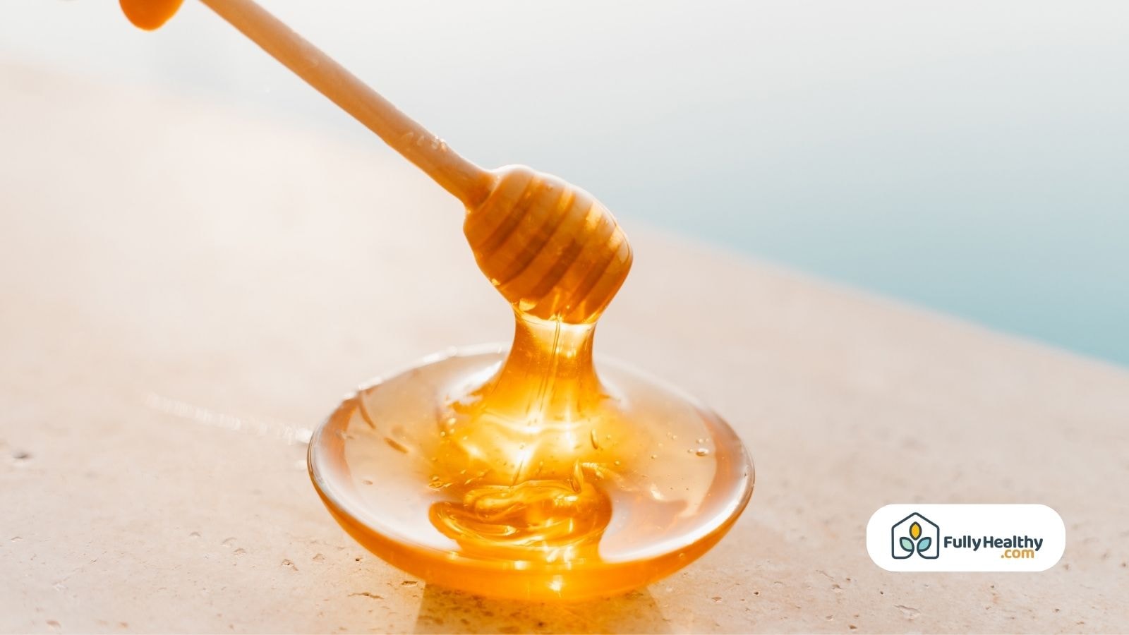 Honey dipper dripping golden honey onto a smooth white plate