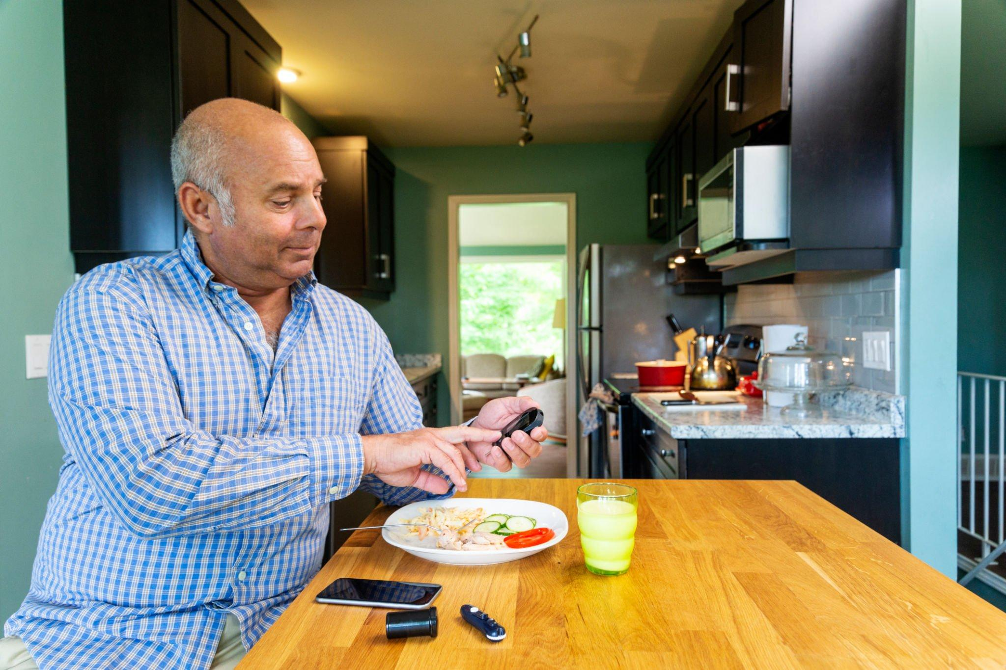 A man closely examining his CGM device, monitoring very high blood glucose levels, a critical factor in diagnosing diabetes.