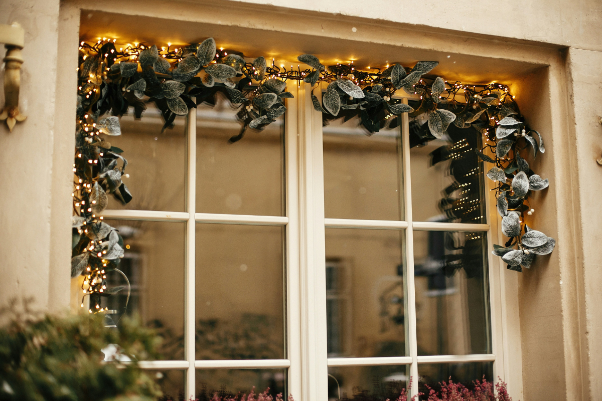 DIY garlands made from dried oranges and fresh greenery for festive window decorations.