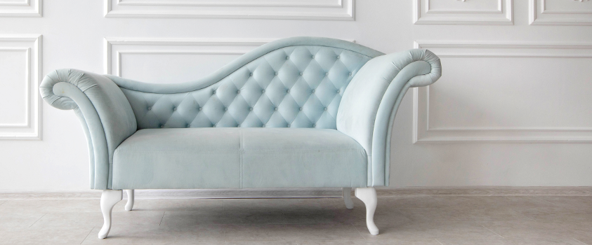 A pale blue chaise lounge with a distinct wave back, ideal for stretching out and relaxing.