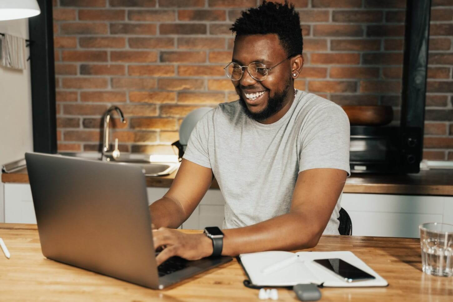 man sitting at a desk with laptop and notebook working on internal communication strategy