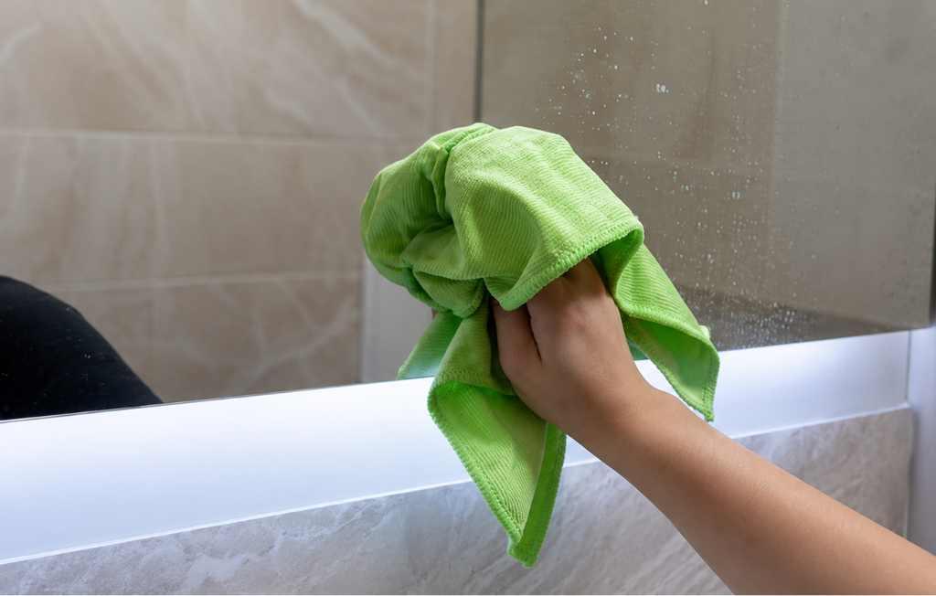 cleaning bathroom mirror with microfiber cloth