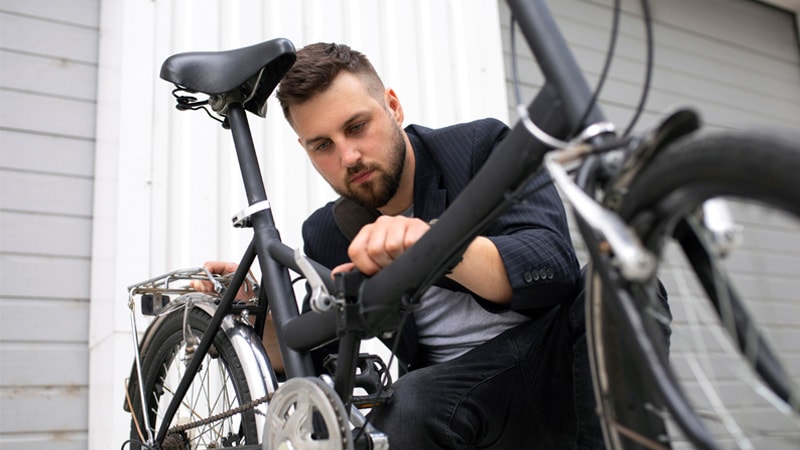 a person inspecting the frame of a matte black foldable bike