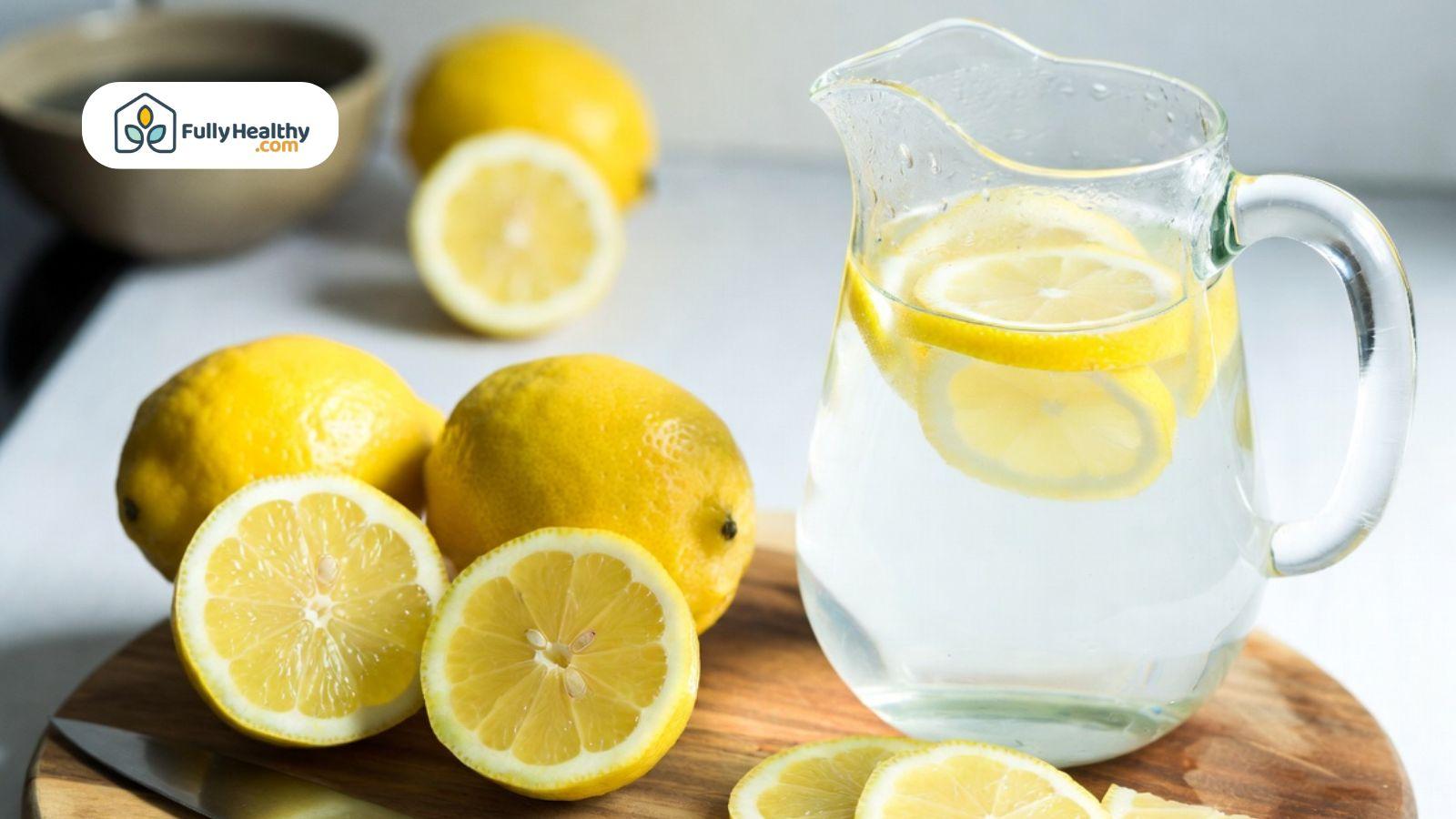 Fresh lemons and a pitcher of lemon-infused water on a countertop.