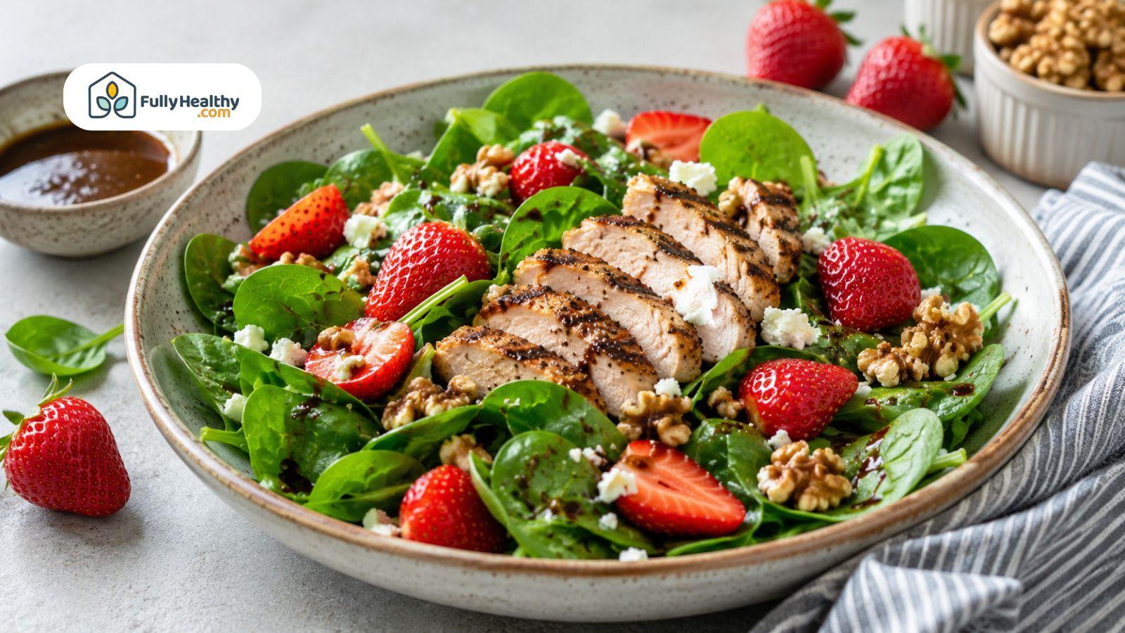 Spinach salad with grilled chicken, strawberries, walnuts, and feta cheese.