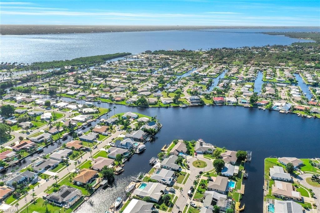 The image depicts a scenic view of waterfront homes in Waterway Estates, North Fort Myers, featuring canal access and private boat docks. This residential community showcases beautiful properties with views of the water, ideal for those looking to buy homes in North Fort Myers, FL.