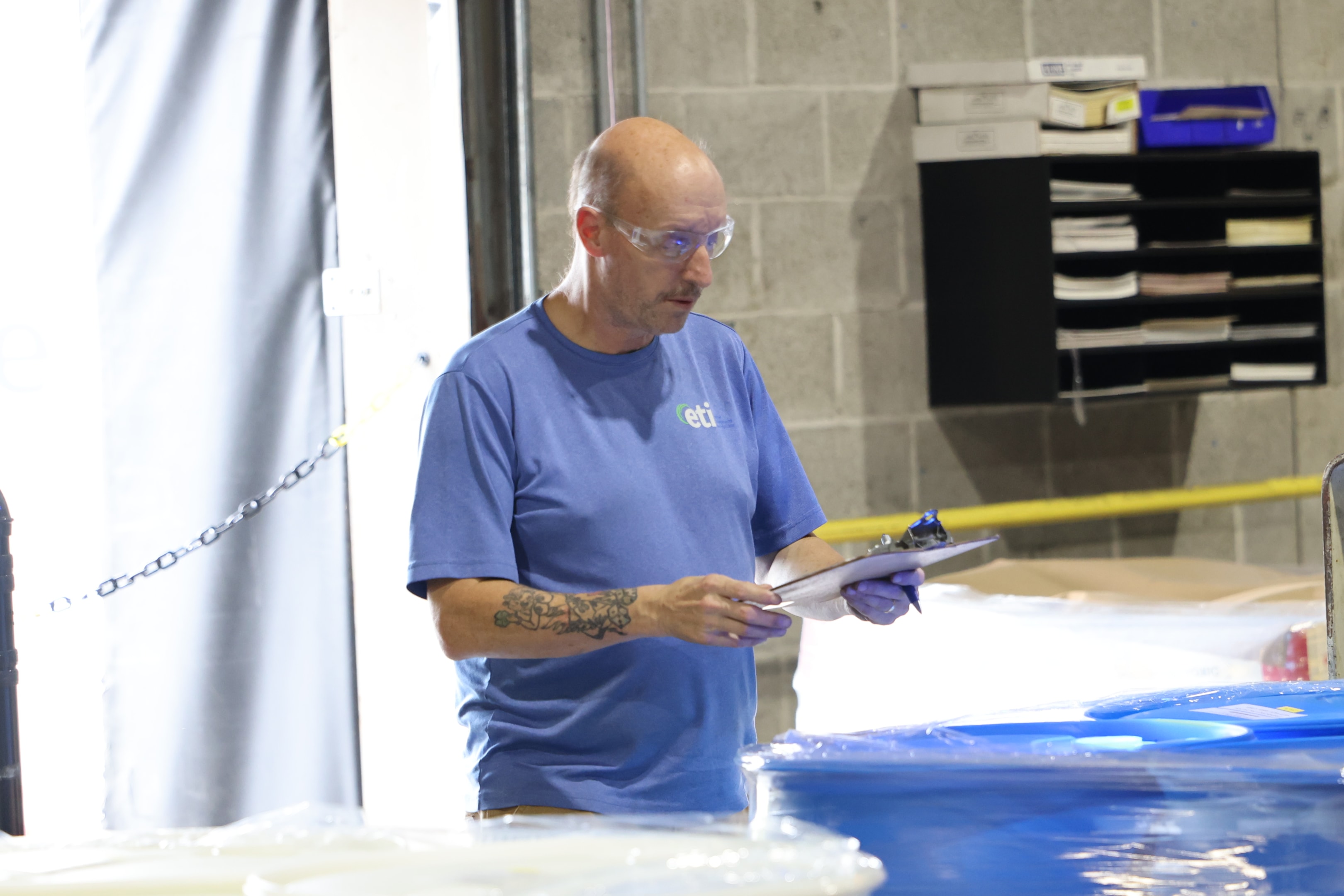 ETI technician in PPE reviewing chemical handling procedures in an industrial facility