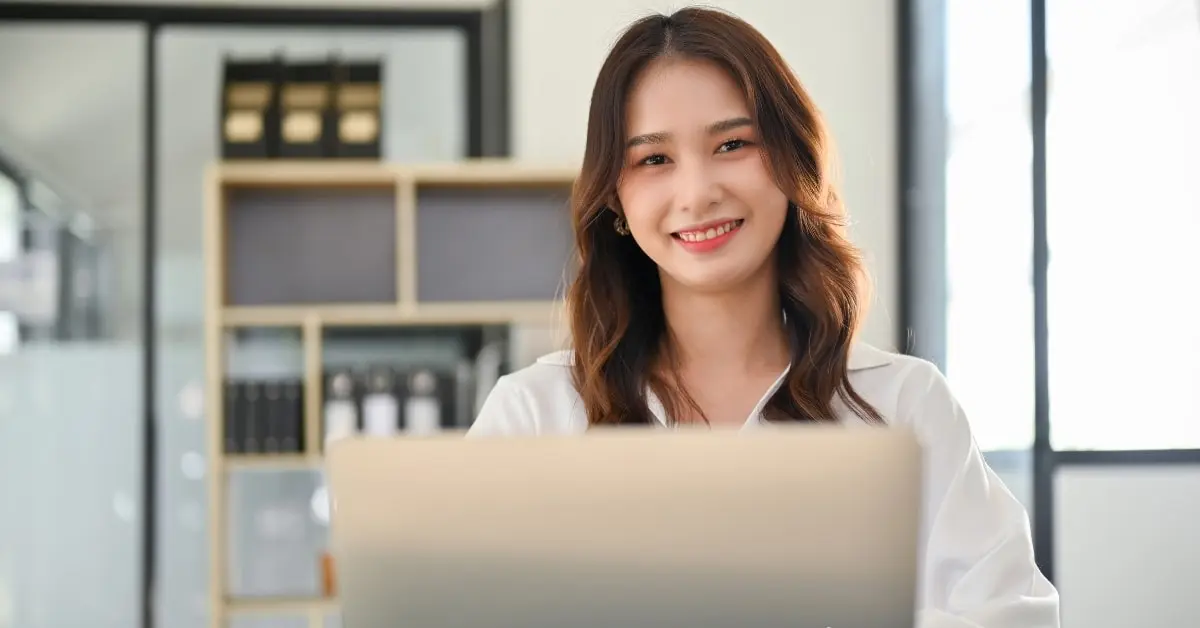 Confident woman at her desk, utilizing top tax resources for OnlyFans creators on her laptop.