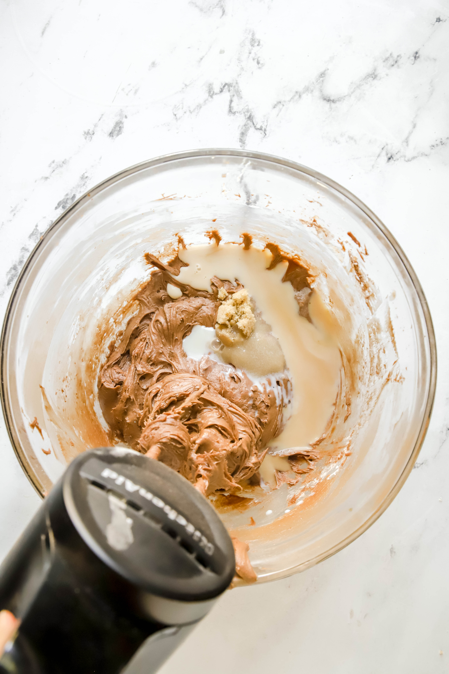 brownie batter dip being mixed in a glass bowl with a hand mixer