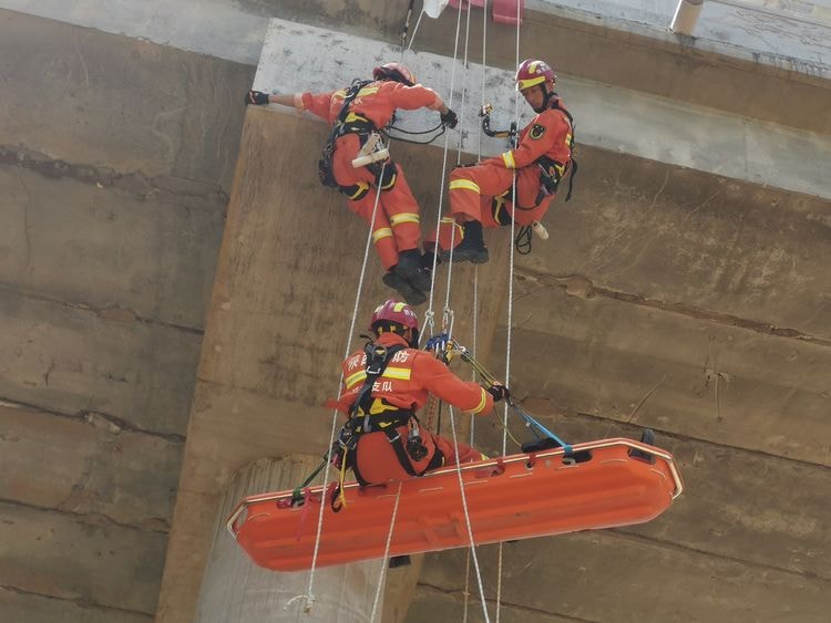 A patient being transported safely using a basket stretcher with safety straps.