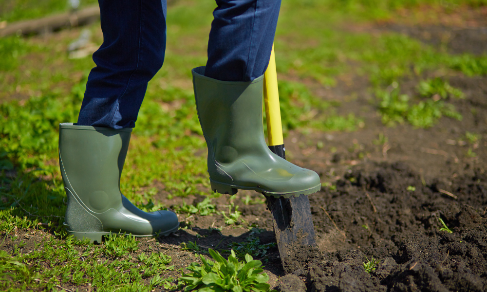 Worker in rubber boots digging with a shovel