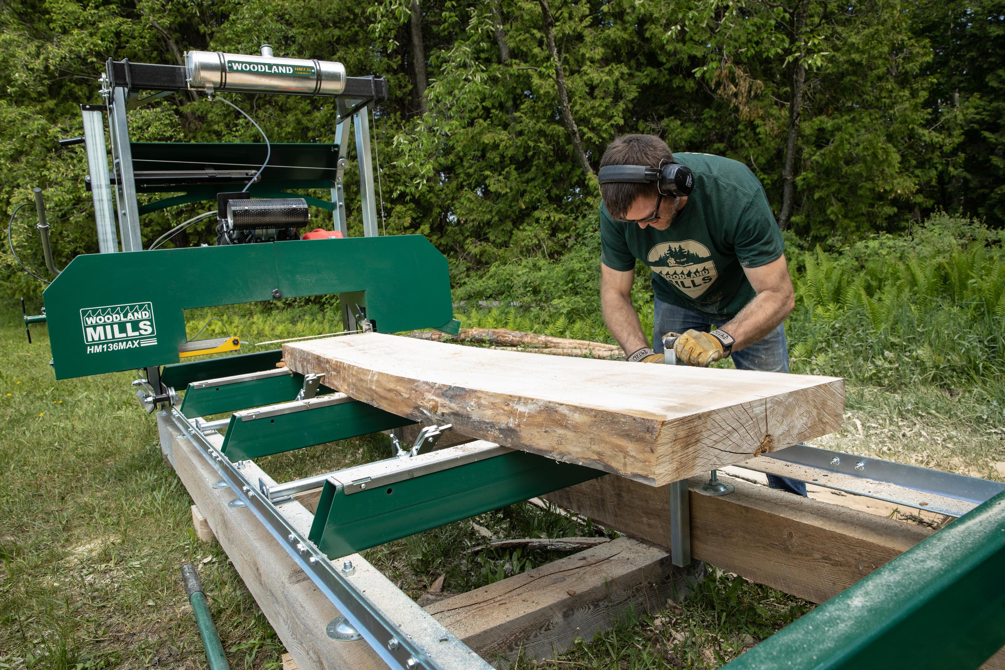 A man adjusting the bunk on his Woodland Mills HM136MAX Portable Sawmill for cutting thin sheets of wood.