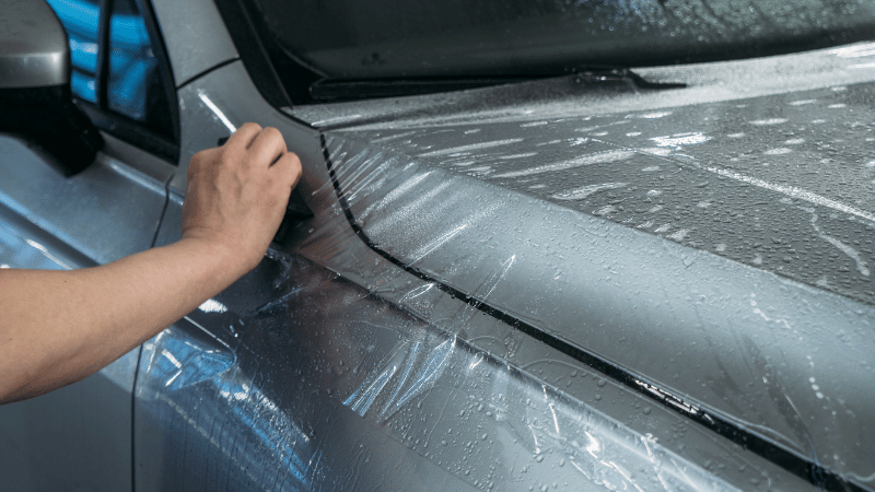 A man is applying the PPF on the car.