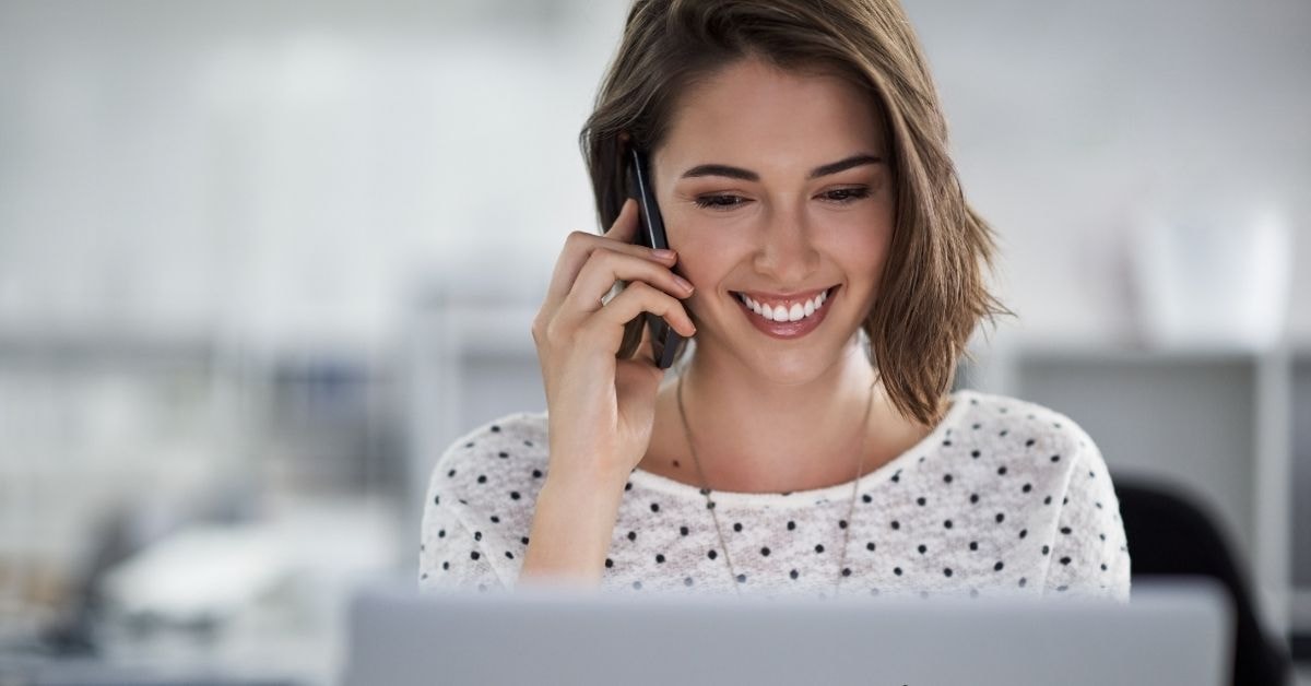 Smiling woman on phone managing finances, benefiting from an LLC for OnlyFans business setup.