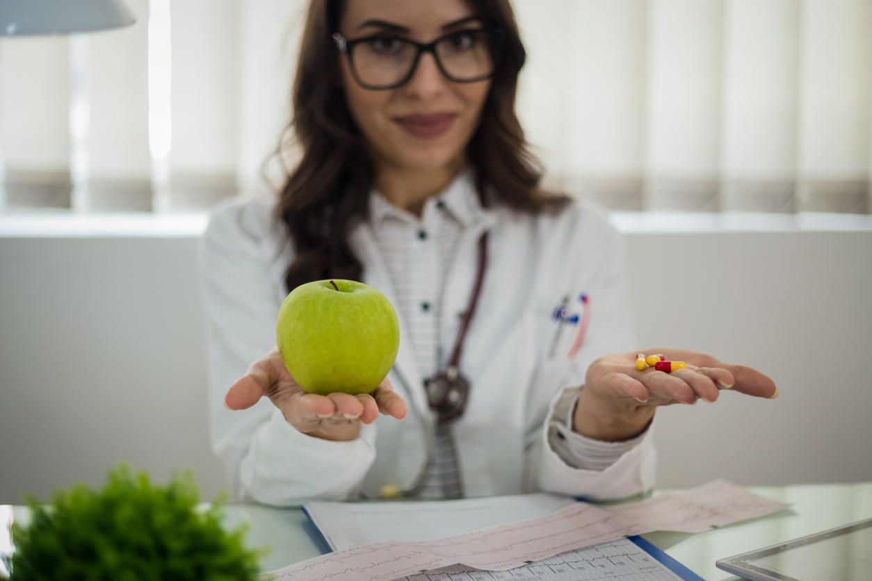 Female doctor compares whole food to supplements. Image MajaMitrovic