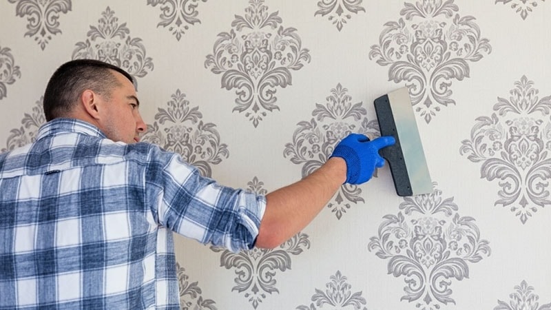 A man wiping a wallpaper wall surface