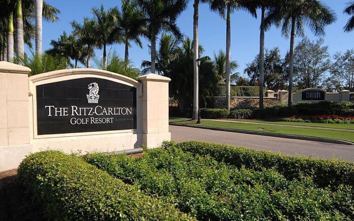 An aerial view of the Tiburon golf community showcases its championship golf courses and luxurious residences, all nestled among lush preserves. The image highlights the resort-style living, complete with world-class amenities, including the Ritz Carlton Golf Resort and Tiburon Golf Club, creating an exceptional private retreat in North Naples.