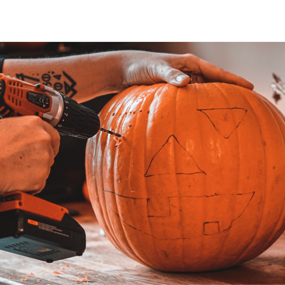 A person carving a pumpkin with a carving knife and a power drill