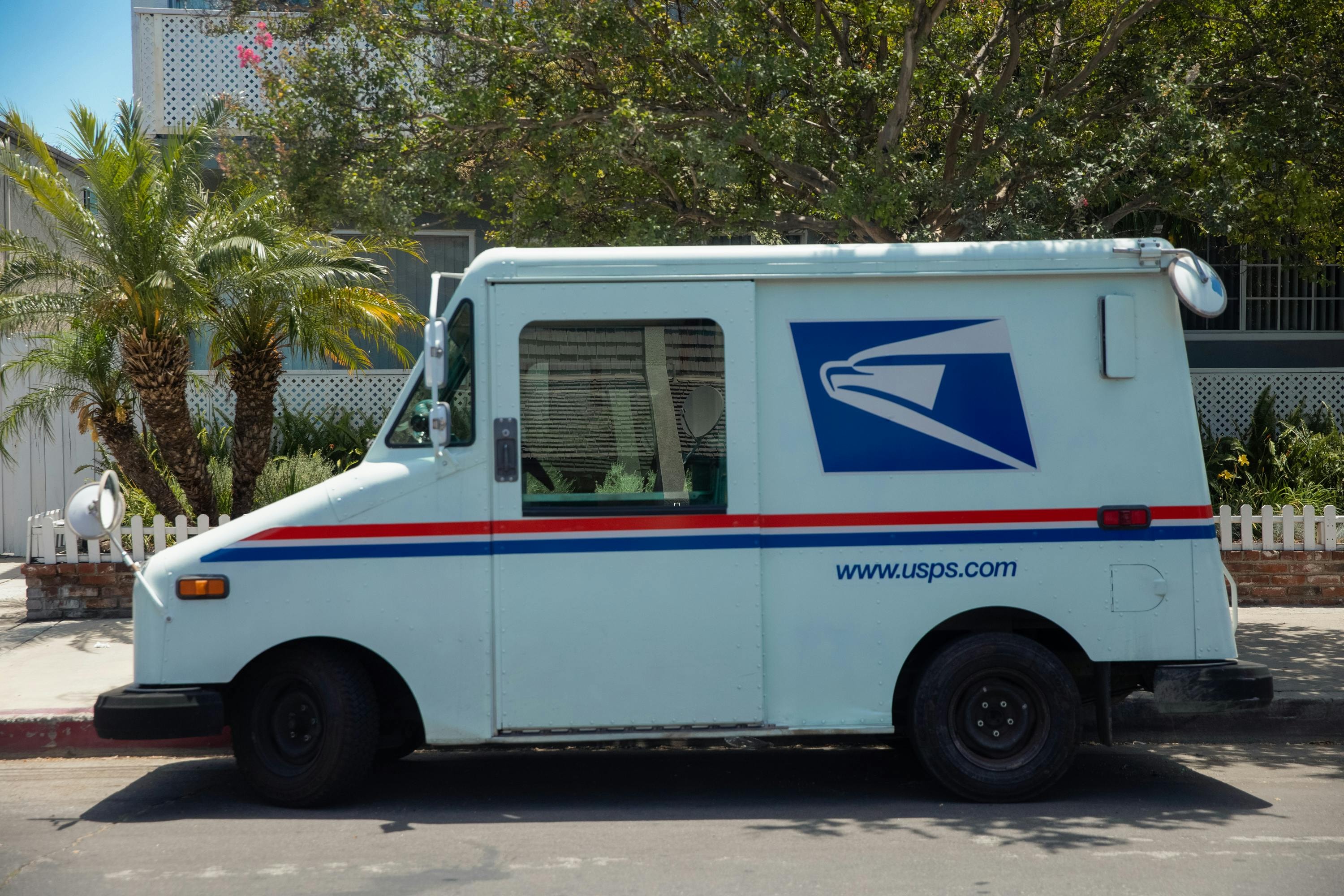 USPS mail truck delivering handwritten style letters as part of a real estate direct mail campaign. 