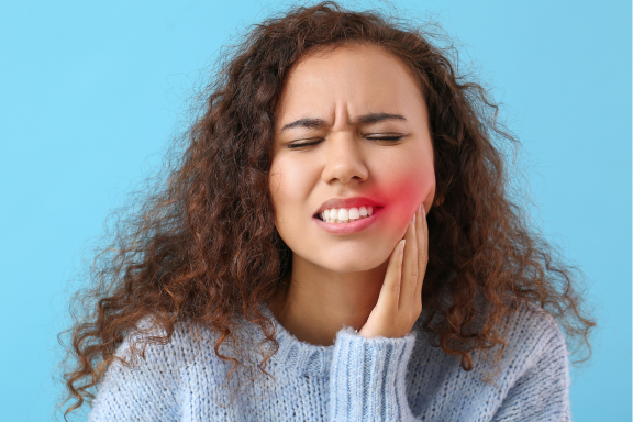 woman holds side of face from wisdom tooth pain 