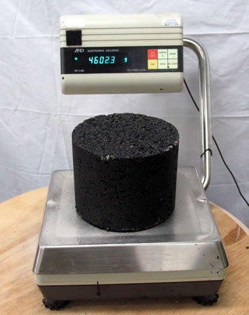 A person measuring bulk specific gravity of a material using a scale