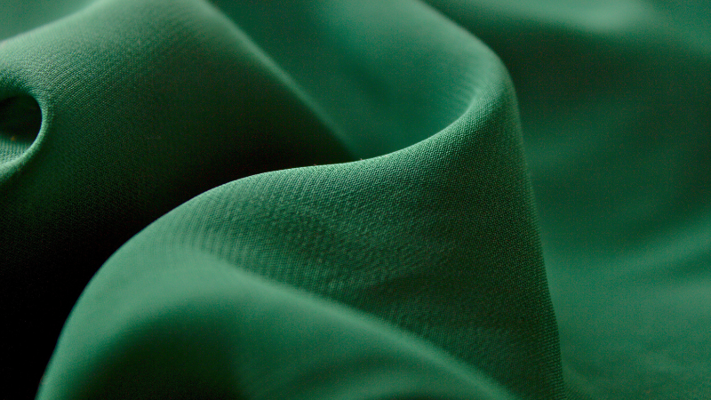 A close up view of a dark green cupro fabric.