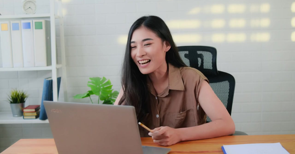 A smiling woman at her desk with a laptop, discussing strategies for managing federal total tax liability.