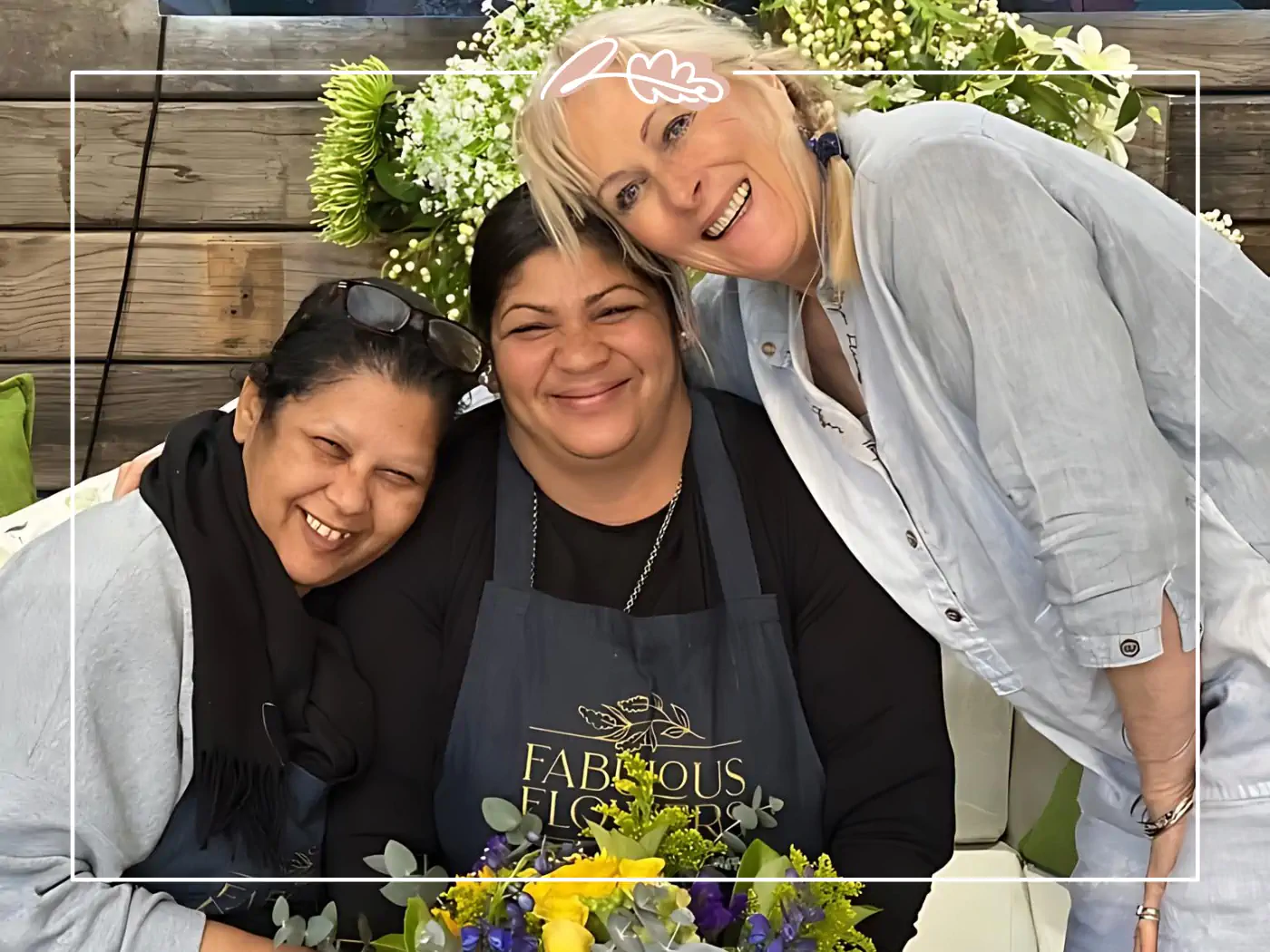 Three florists at Fabulous Flowers and Gifts enjoying a moment together with a vibrant bouquet of yellow and purple flowers. Your Perfect Bouquet of Flowers, a stunning fresh gift.