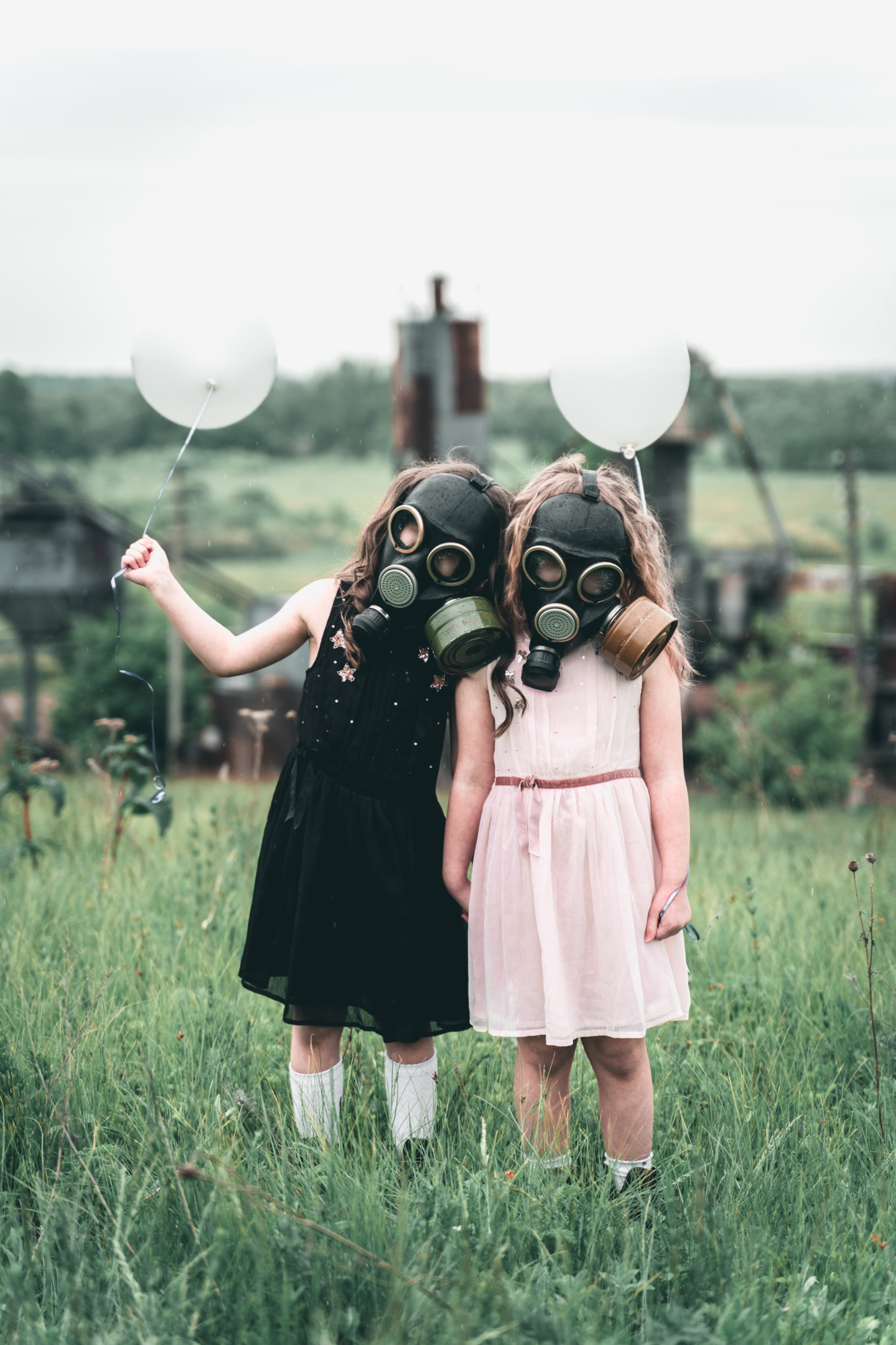 two girls wearing gas masks, holding balloons